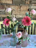 Διακοσμητικό τραπεζιού με βαζάκια απο φυσικά λουλούδια ζέρμπερες και τριαντάφυλλα.